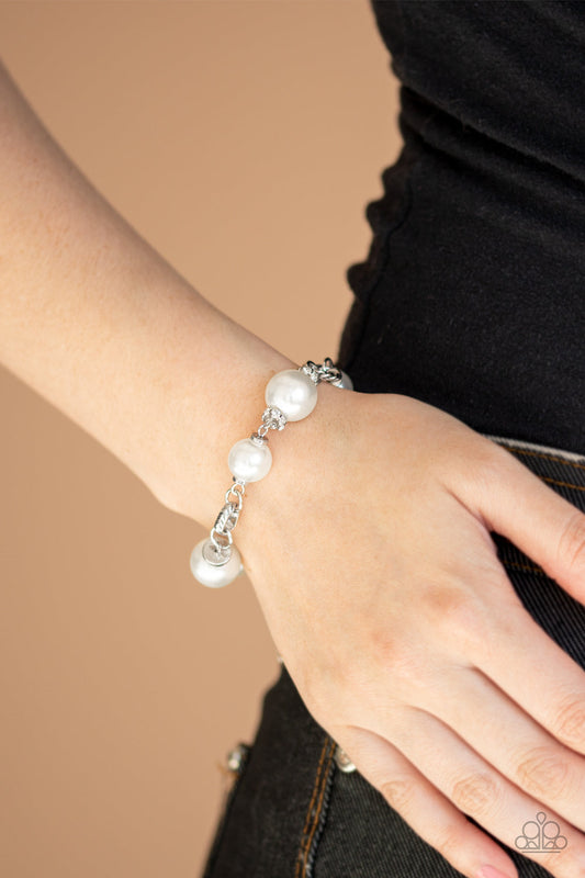 Boardroom Baller - White Pearl and Silver Bracelet - Paparazzi Accessories - A classic collection of white pearls, white rhinestone encrusted rings, and ornate silver accents link across the wrist for a timeless look. Features an adjustable clasp closure. Sold as one individual bracelet.