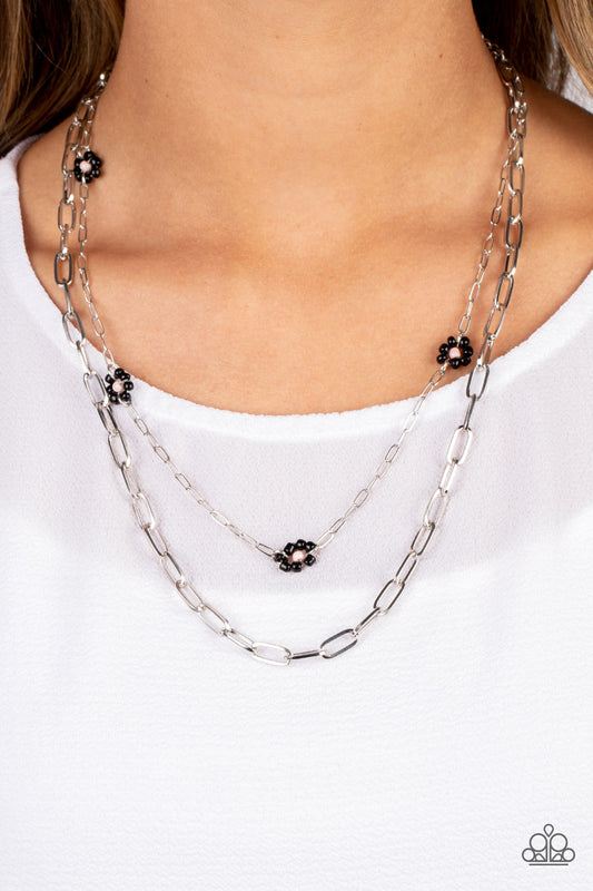 Bold Buds - Black and Silver Flower Necklace - Paparazzi Accessories - Elongated silver ovals link together to create an industrially edgy sheen below the collar. A slightly daintier version of the same style of chain layers above, dotted with black seed bead flowers with pink centers that add playful pops of color along the way. Features an adjustable clasp closure.