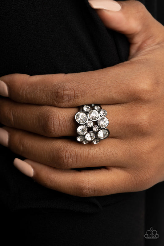 Bubbling Bravado - Black Gunmetal - Sparkly Ring - Paparazzi Accessories - Sleek gunmetal frames, a bubbly collection of sparkly white rhinestones coalesces into a glamorous band across the finger. Features a stretchy band for a flexible fit. Sold as one individual ring.