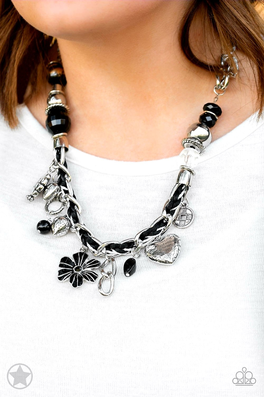 Charmed, I Am Sure Black Necklace - Paparazzi Accessories - Black and ivory cording is braided through a chunky silver chain. A unique variety of charms decorate the piece including a delicate flower and a heart. Heart is inscribed with the phrase "With All My Heart"on one side and a short bible verse on the other that reads, "Love the Lord thy God with all your heart. Luke 10:27." Features an adjustable clasp closure.Includes necklace and one pair of matching earrings.