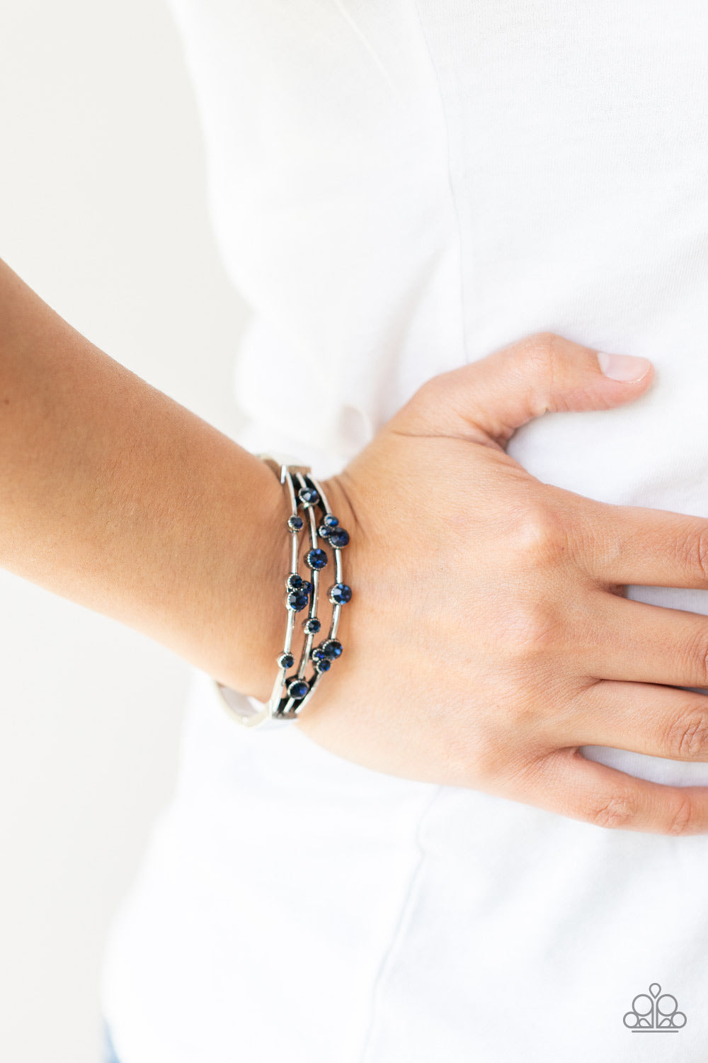 ​Cosmic Candescence - Blue Rhinestone - Silver - Hinged Closure Bracelet - Paparazzi Accessories - 
A smattering of glittery blue rhinestones adorn three silver bars that coalesce into a versatile silver cuff-like bangle around the wrist. Features a hinged closure.
Sold as one individual bracelet.

