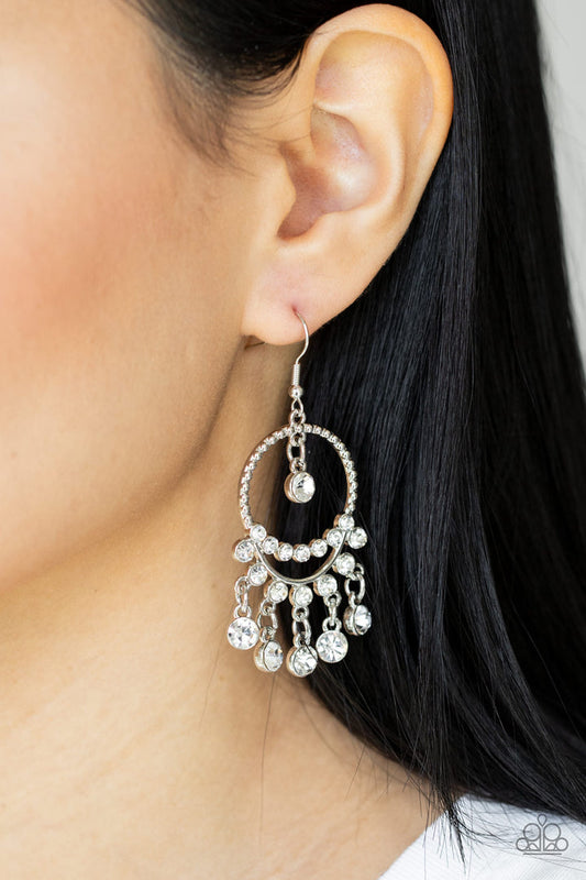 Cosmic Chandaliers - White and Silver Earrings - Paparazzi Accessories - Glassy white rhinestones swing from a row of glittery white rhinestones that attach to the bottom of a studded silver hoop. An additional row of blinding white rhinestones bows across the display, adding extra sparkle to the glamorous chandelier. Earring attaches to a standard fishhook fitting. Sold as one pair of earrings.
