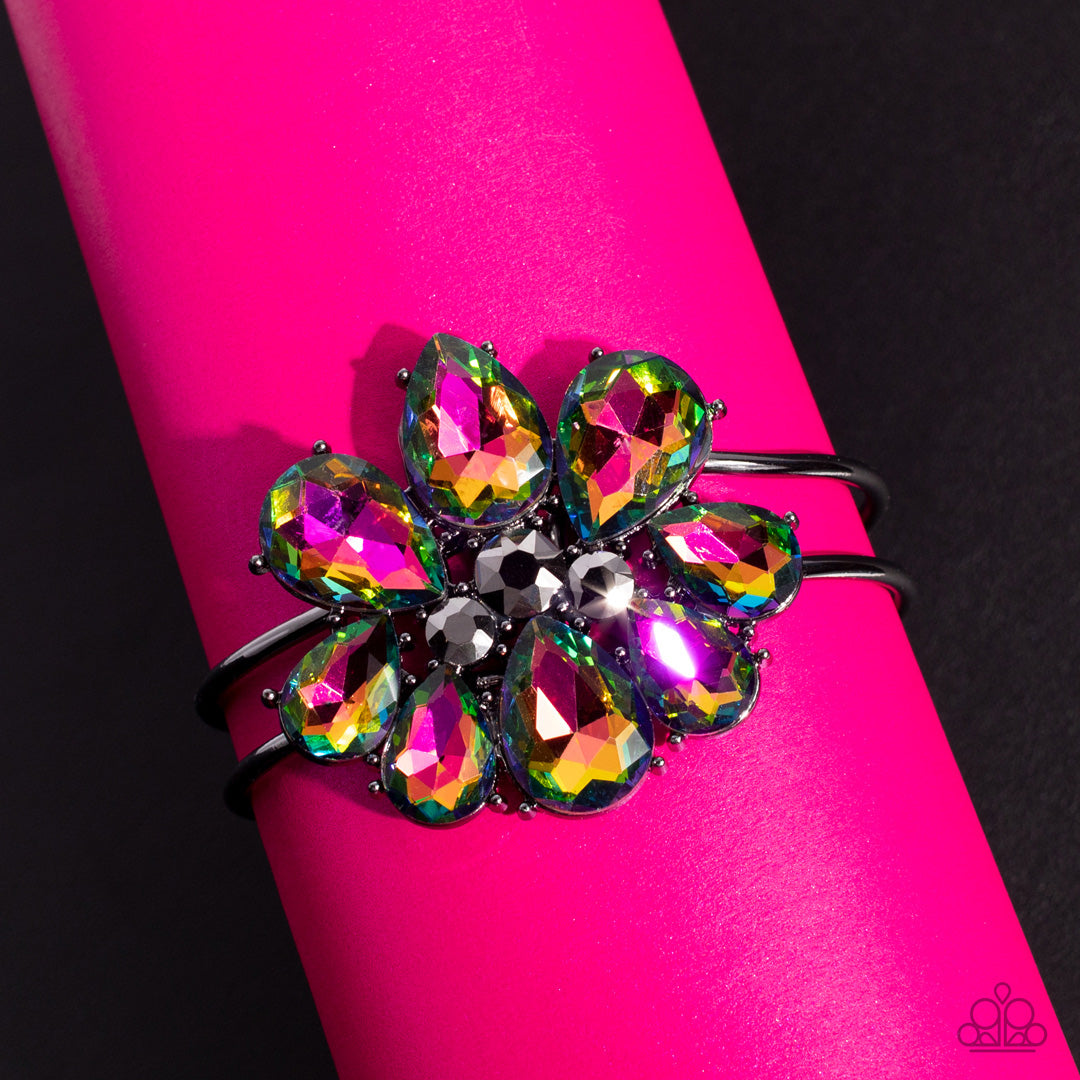 DAUNTLESS is More - Oil Spill Multi Color - Floral Bracelet - Paparazzi Accessories - A dazzling collection of oil spill teardrop gems fan out around hematite, creating an explosion of sparkle. The exaggerated gems circle into a floral centerpiece atop a pair of skinny gunmetal bars that wrap around the wrist in an airy finish. Features a hinged closure.