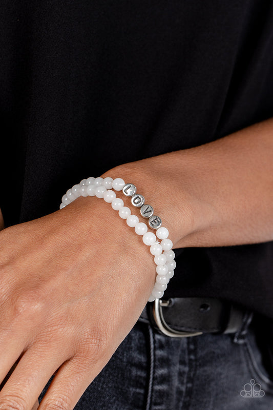 Devoted Dreamer - White and Silver Bracelet - Paparazzi Accessories - Cloudy beads in subtle shades of white extend around the wrist on elastic stretchy bands for a two-for-one romantic stack. Centered on one of the white bracelets, silver discs stamped with individual black letters spell out the word "love." Sold as one individual bracelet.