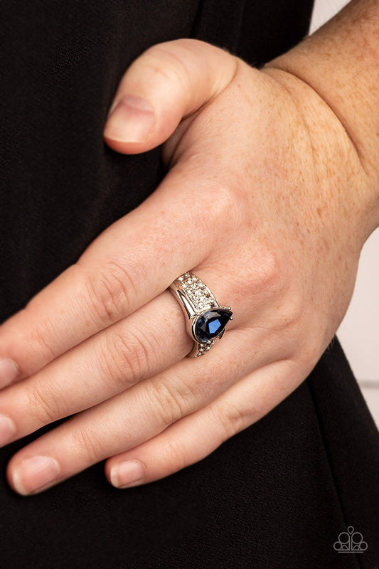 Dive into Oblivion - Blue and Silver Ring - Paparazzi Accessories - Swathed in rows of dainty white rhinestones, an asymmetrical silver band is adorned with a bedazzling Skydiver teardrop rhinestone for a regal finish. Features a dainty stretchy band for a flexible fit.