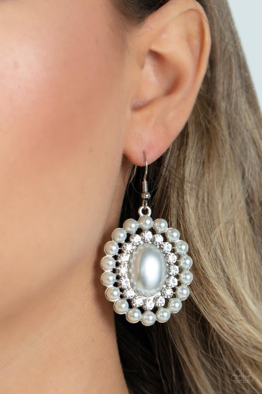 Dolled Up Dazzle - White Pearl and Silver Earrings - Paparazzi Accessories - Borders of bubbly white pearls and glassy white rhinestones encircle an oversized pearly white oval bead, resulting in a refined shimmer. Earring attaches to a standard fishhook fitting. Sold as one pair of earrings.