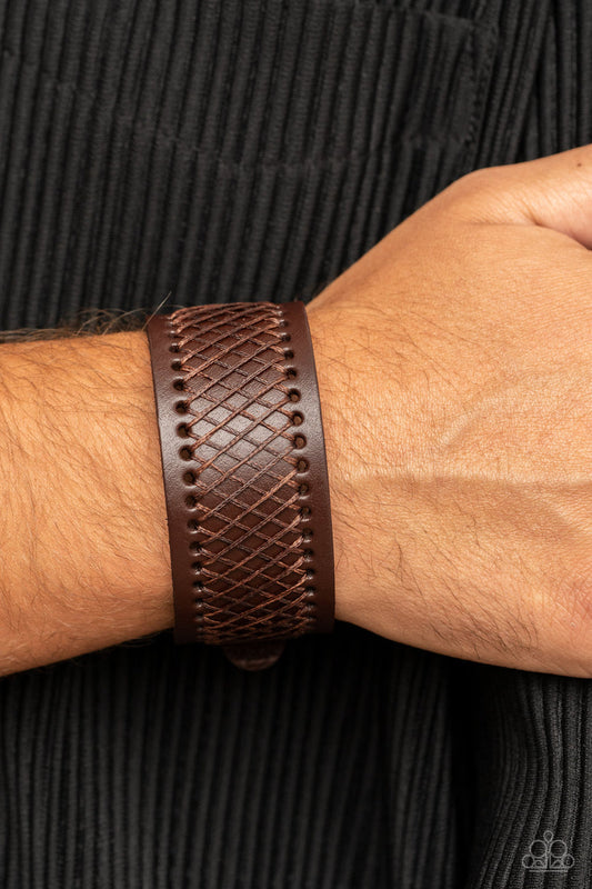 Drifter Discovery  - Brown Urban Leather Bracelet - Paparazzi Accessories - Shiny brown cording boldly crisscrosses across the front of a thick brown leather band, creating an edgy centerpiece around the wrist. Features a buckle closure.
