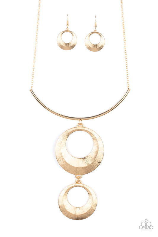 Egyptian Eclipse - Gold Fashion Necklace - Paparazzi Accessories - Blinding scratch finish, two beveled gold circular frames swing from the bottom of a bowing gold rod, creating an edgy stacked pendant down the chest. Features an adjustable clasp closure fashion necklace. 