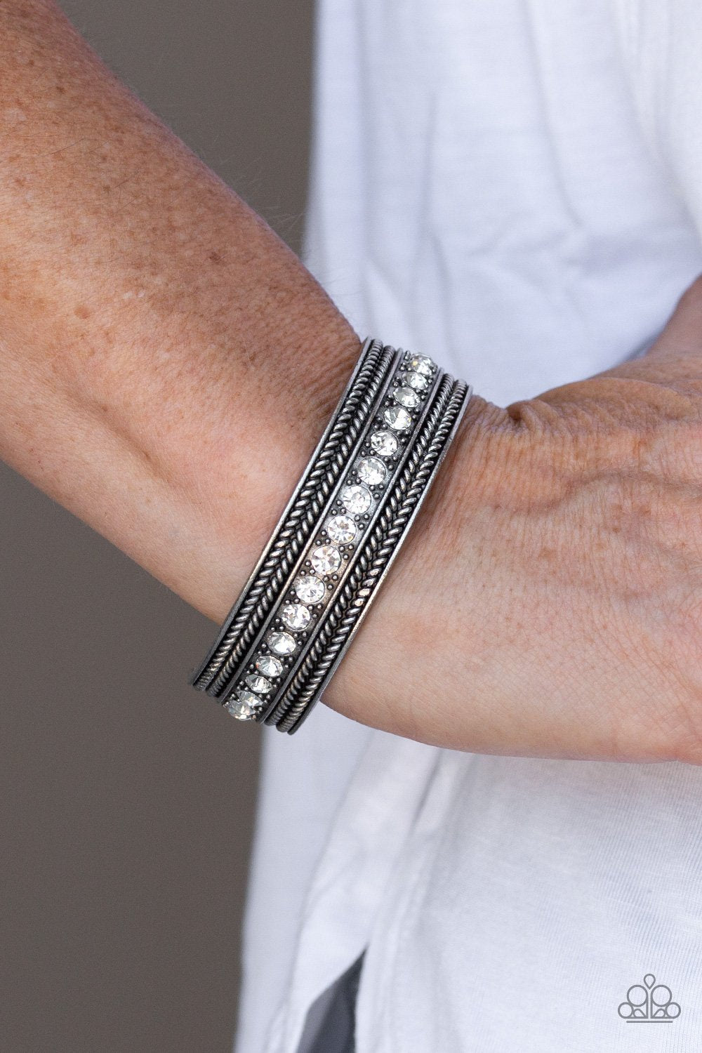 Empress Etiquette - White and Silver Cuff Bracelet - A row of glittery white rhinestones line the center of a studded silver cuff for an edgy look. Sold as one individual bracelet. Trendy fashion jewelry for everyone.