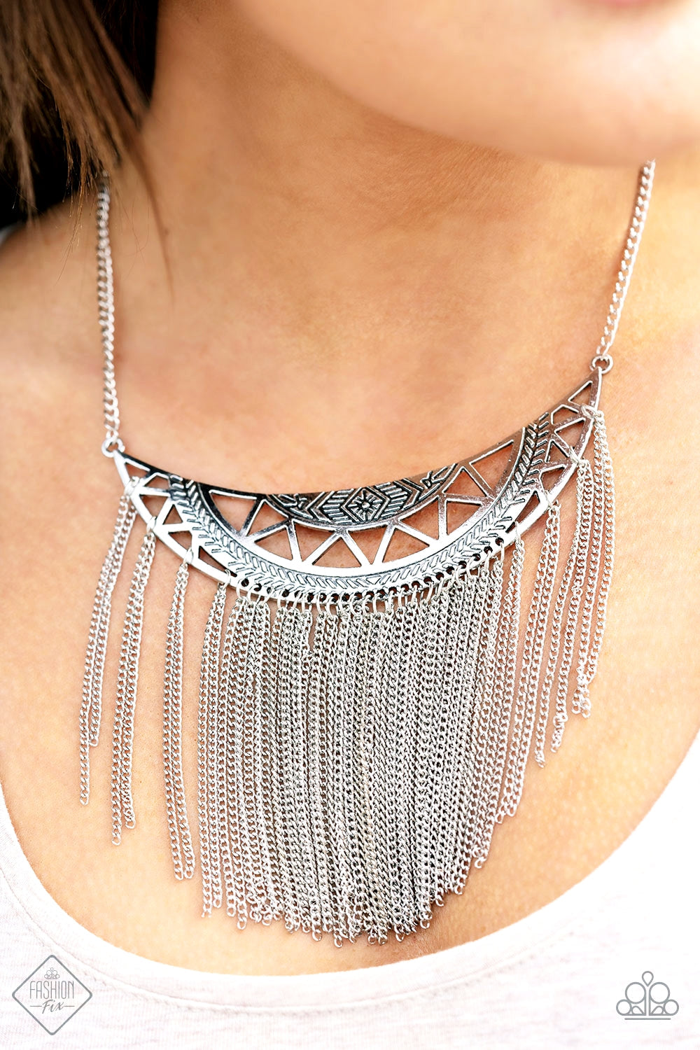 Empress Excursion - Silver Necklace - Paparazzi Accessories - A stenciled silver crescent stamped in tribal inspired patterns swings unapologetically below the collar. A curtain of shimmery silver chains cascades from the bottom of the dramatic pendant, creating a bold fringe with endless movement. Features an adjustable clasp closure. Sold as one individual necklace.