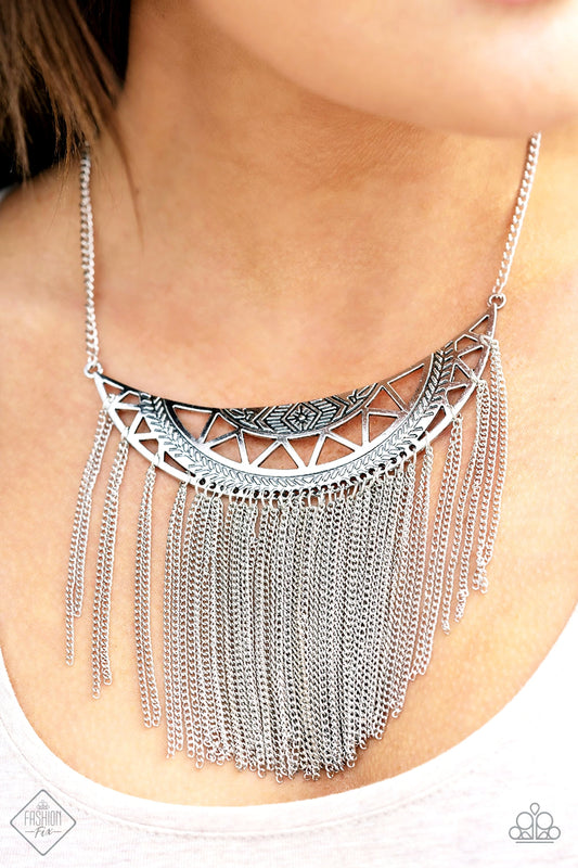 Empress Excursion - Silver Necklace - Paparazzi Accessories - A stenciled silver crescent stamped in tribal inspired patterns swings unapologetically below the collar. A curtain of shimmery silver chains cascades from the bottom of the dramatic pendant, creating a bold fringe with endless movement. Features an adjustable clasp closure. Sold as one individual necklace.