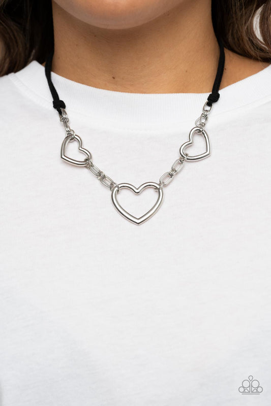 Fashionable Flirt - Black Suede - Silver Heart Necklace - Paparazzi Accessories - Strands of black suede knot around sections of chunky silver chains that have been adorned in oversized silver heart frames, resulting in a flirtatious display below the collar. Features an adjustable clasp closure. Sold as one individual necklace.
