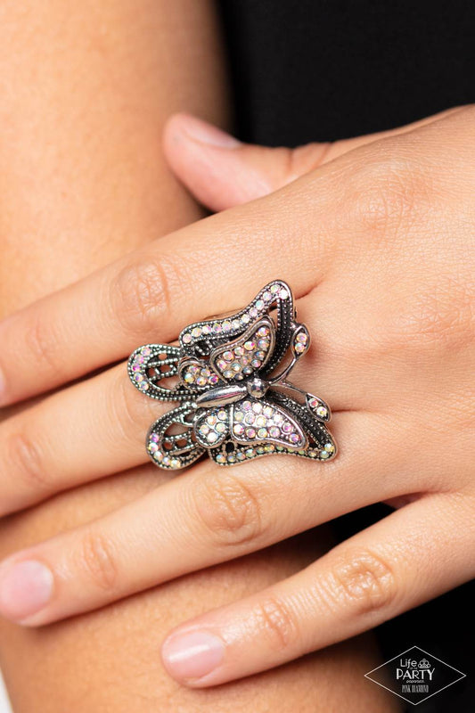 Free To Fly - Multi Color Iridescent - Butterfly Ring - Paparazzi Accessories - Dazzling iridescent rhinestones are sprinkled across the wings of a silver butterfly, creating a whimsical frame atop the finger. Features a stretchy band for a flexible fit.