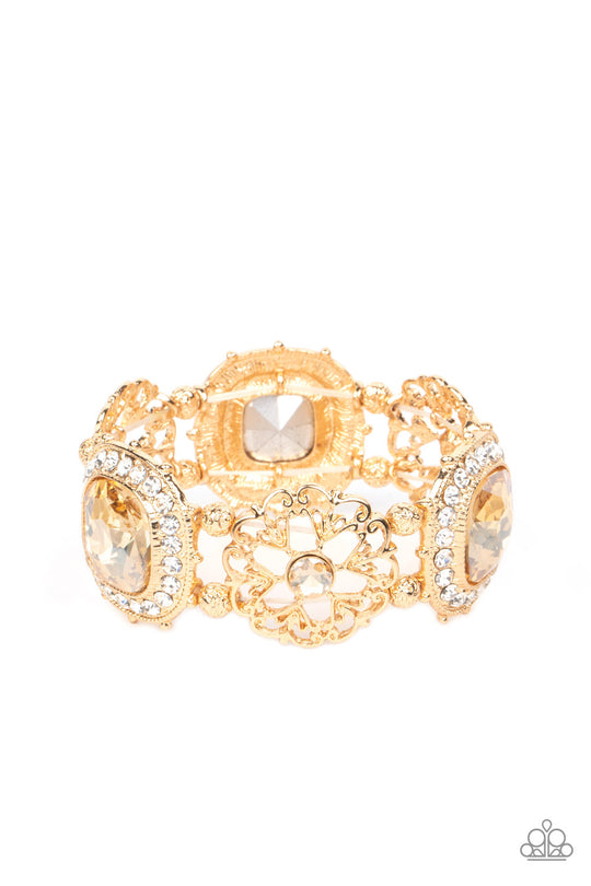 Glided Gallery - Gold Floral Gem Bracelet - Paparazzi Accessories - Oversized faceted golden gems in dramatically rounded square cuts are wrapped in borders of classic white rhinestones, emitting a breathtaking sheen. Floral-inspired frames, dotted with solitaire golden rhinestones, bloom in between the large rhinestones, adding airy accents to the bold design, as textured gold beads separate each frame as they're threaded along stretchy elastic bands. Sold as one individual bracelet.