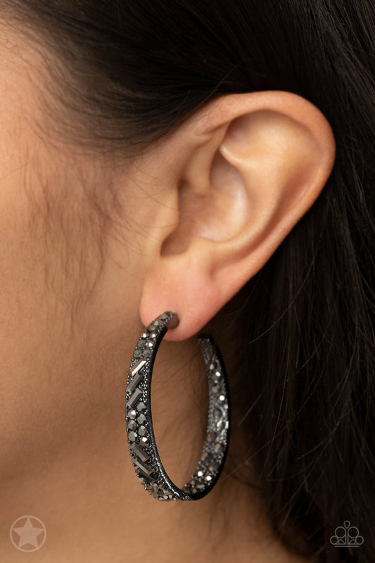 GLITZY By Association - Black - Gunmetal Hoop Earrings - Paparazzi Accessories - The front facing surface of a chunky gunmetal hoop is dipped in brilliantly sparkling hematite rhinestones while light-catching texture wraps around the back. The interior of the hoop features the opposite pattern, creating the illusion of a full hoop of blinding shimmer. Earring attaches to a standard post fitting. Hoop measures 1 3/4" in.
