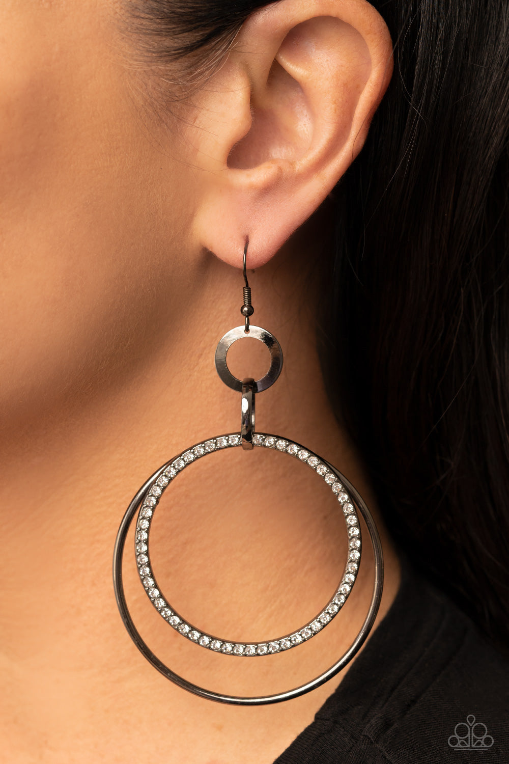 Haute Hysteria - Black Metal Fashion Earrings - Paparazzi Accessories - A white rhinestone encrusted gunmetal ring and glistening gunmetal hoop swings from the bottom of mismatched gunmetal rings, rippling into a dizzying and dazzling oversized hoop. Earring attaches to a standard fishhook fitting. Sold as one pair of earrings. 
