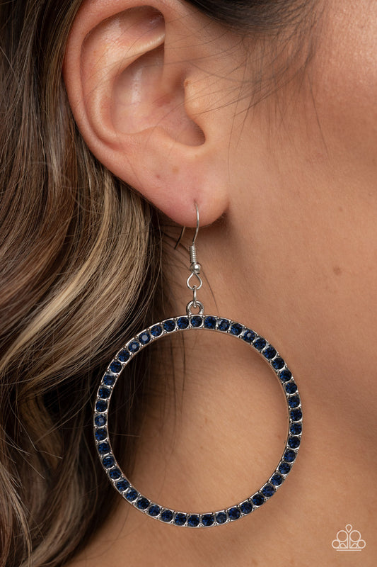 Head-Turning Halo - Glitzy Blue and Silver Earrings - Paparazzi Accessories - The front of an oversized silver ring is encrusted in glitzy blue rhinestones, resulting in a head-turning hoop. Earring attaches to a standard fishhook fitting. Sold as one pair of earrings.