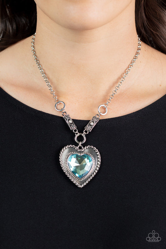 Heart Full of Fabulous - Blue Gem - Silver Necklace - Paparazzi Accessories - An oversized blue heart gem is pressed into a silver heart frame below the collar. The flirtatious pendant attaches to silver rings and decorative silver frames dotted in white rhinestones, resulting in a dash of vintage inspired romance. Features an adjustable clasp closure.