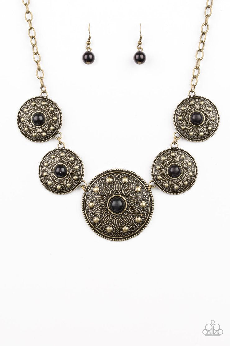 Hey, SOL Sister - Black and Brass Necklace - Paparazzi Accessories - Gradually increasing in size near the center, round brass frames radiating with sunburst patterns link below the collar. Infused with shiny brass studs, the tribal inspired frames are dotted with black beaded centers for a colorful finish. Features an adjustable clasp closure fashion necklace.