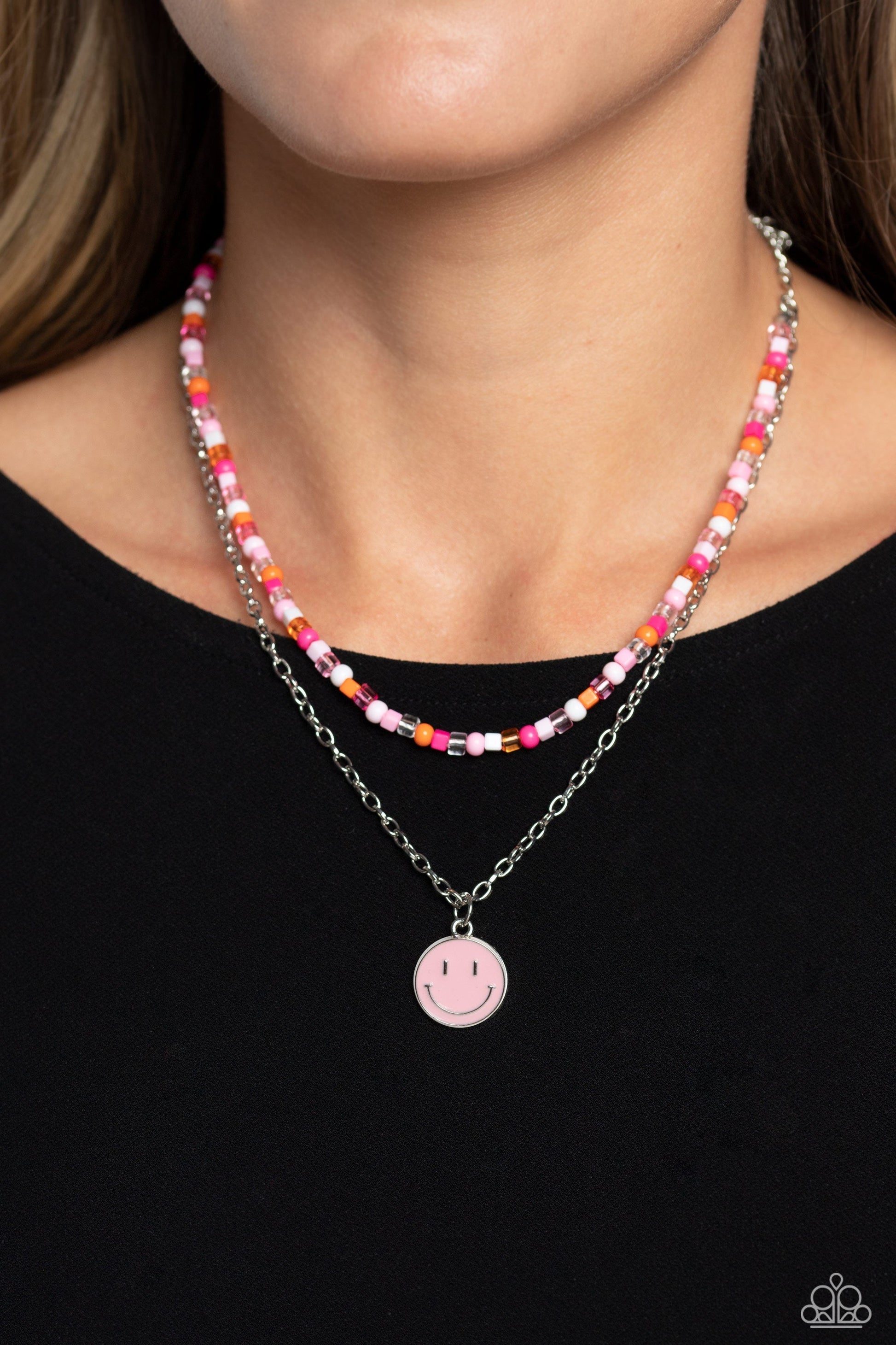 High School Reunion - Pink Seed Bead Necklace - Paparazzi Accessories - Gliding from a dainty, silver chain, a smiley face pendant stands out against a pink backdrop. Completing the charismatic ensemble, a collection of seed beads in shades of light pink, white, pink, orange, and hot pink create bright pops of color around the neckline for a youthful finish.