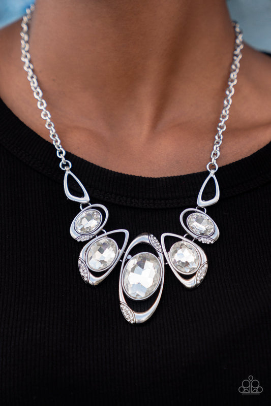 Hypnotic Twinkle - White Gem and Silver Necklace - Paparazzi Accessories - This stunning gem necklace is stunning and great for any occasion or everyday casual wear.  It's dusted in sections of glassy white rhinestones, asymmetrical silver frames curl around oversized white gems below the collar. Varying in shape, the mismatched frames increase in size as they near the center for a hypnotizing fashion necklace.