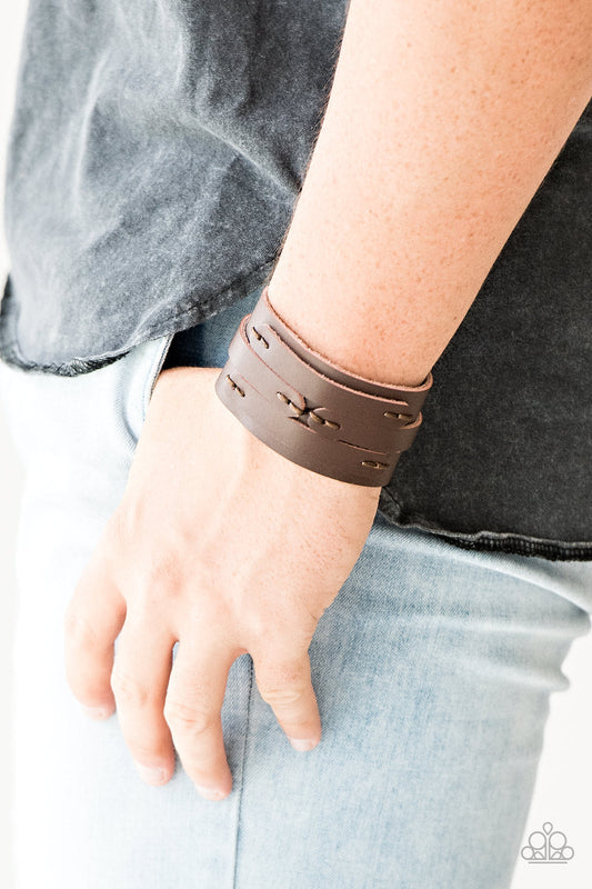 In or OUTLAW - Brown Leather Urban Bracelet - Paparazzi Accessories -
Pieces of brown leather are stitched in place across the front of a thick brown leather band for a rugged look. Features an adjustable snap closure.
