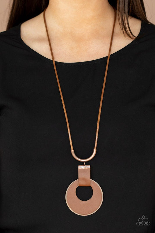 Luxe Crush - Copper Brown - Leather Necklace - Paparazzi Accessories - A large cutout copper disc, overlaid with brown leather, is cradled in a wide brown leather strap. The luxe pendant sways from a U-shaped copper cylinder threaded along the end of a lengthened polished brown cord for an indulgently lavish finish. Features a sliding bead closure.