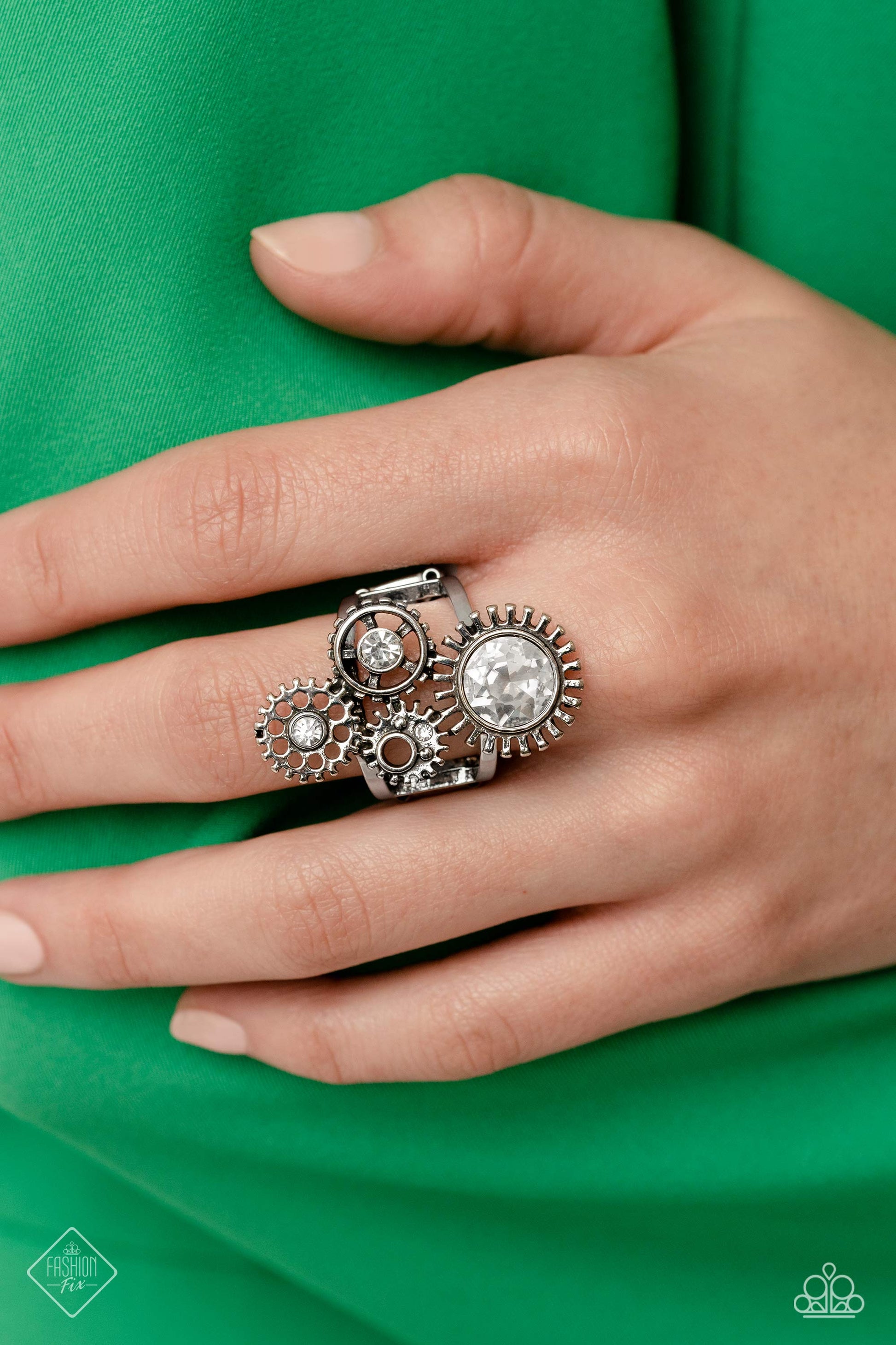 Magnificent Musings - Silver Jewelry Set - Paparazzi Accessories - Centered atop a pair of arcing silver bands, four gear pendants with varying textures, details, sizes, and a dusting of gems climb up the finger for a steampunk-styled centerpiece. Features a stretchy band for a flexible fit. Sold as one individual ring.
