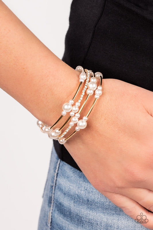 Marina Masterpiece - Gold and Pearl Coil Bracelet - Paparazzi Accessories - P9RE-GDXX-319XX - Bubbly white pearls, cylindrical gold beads, and glassy white rhinestones are threaded along a coiled wire, resulting in a timeless infinity wrap bracelet around the wrist. Sold as one individual bracelet.
