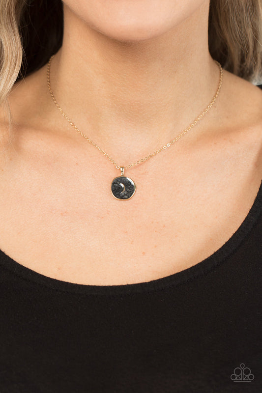 Moon Magic - Black and Gold Necklace - Paparazzi Accessories - Painted in a shimmery black lacquer finish, an asymmetrical gold disc is dotted in a dainty gold moon accent as it swings from the bottom of a dainty gold chain below the collar for an enchanting finish.