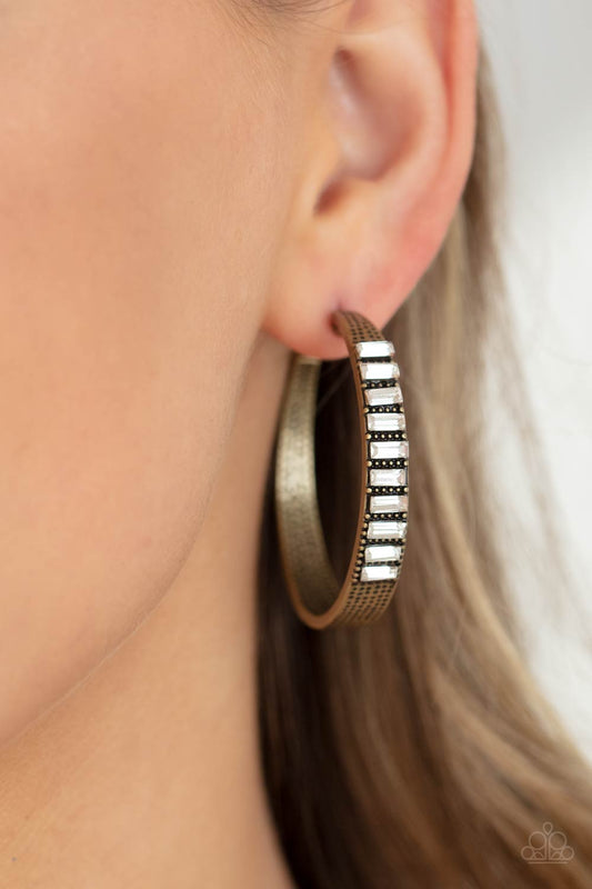 More To Love - Brass Hoop Earrings - Paparazzi Accessories - The top half of a thick textured brass frame is lined in a stack of emerald cut white rhinestones, creating an unexpected pop of shimmer. Earring attaches to a standard post fitting. Hoop measures approximately 1 3/4” in diameter. Sold as one pair of hoop earrings.