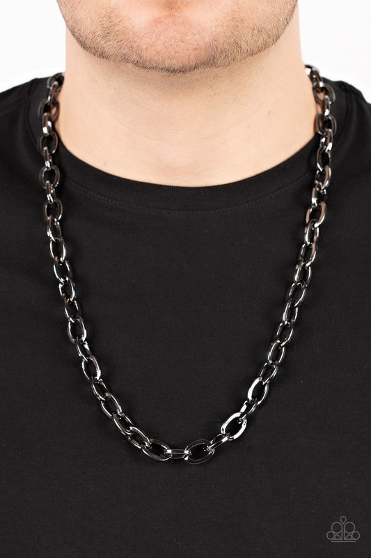 Player of the Year - Black Mens Necklace - Paparazzi Accessories - A dramatically oversized collection of oval gunmetal links boldly interlock across the chest, resulting in an intense industrial centerpiece.