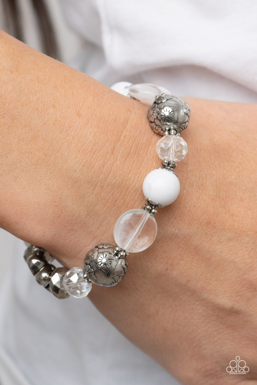 Pretty Persuasion - Iridescent White and Silver Bracelet - Paparazzi Accessories - Enchanting assortment of silver floral beads and studded silver rings join an opaque, glassy, and iridescent assortment of white beads along a stretchy band around the wrist.
