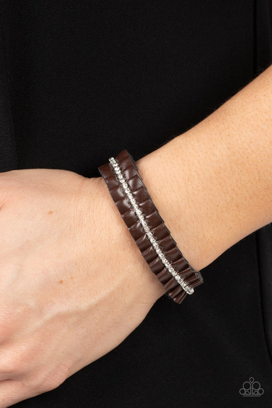 Pretty, Pretty PLEATS - Brown Bracelet - Paparazzi Accessories - A brown leather ribbon delicately gathers into pleats around the wrist. A glittery strand of white rhinestones adorns the center of the pleats, adding a glitzy accent to the textured centerpiece. Features an adjustable sliding knot closure. Sold as one individual bracelet. 