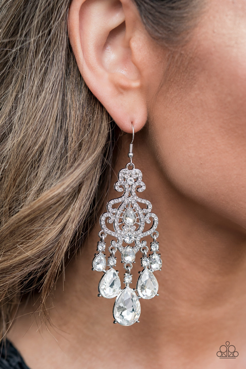 Queen Of All Things Sparkly - White and Silver Earrings - Paparazzi Accessories - Gradually increasing in size, glassy white teardrop gems create a dramatic fringe at the bottom of a decorative silver frame swirling with dainty white rhinestones for a timelessly over-the-top sparkle. Earring attaches to a standard fishhook fitting. 
