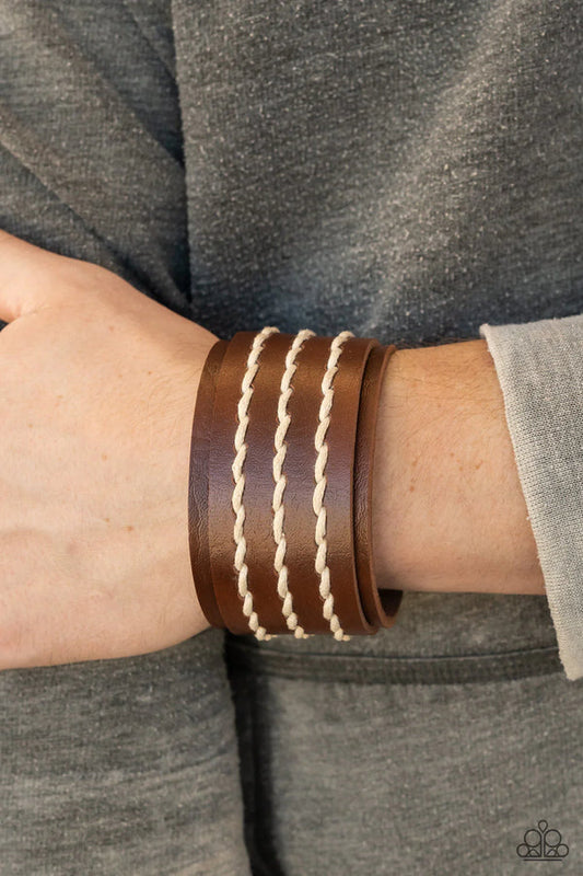 Real Ranchero - Brown Urban Leather Bracelet - Paparazzi Accessories - Three rows of white cording are laced down the center of a brown leather band that is studded in place across the front of a thick leather band, resulting in a rustic flair around the wrist. 