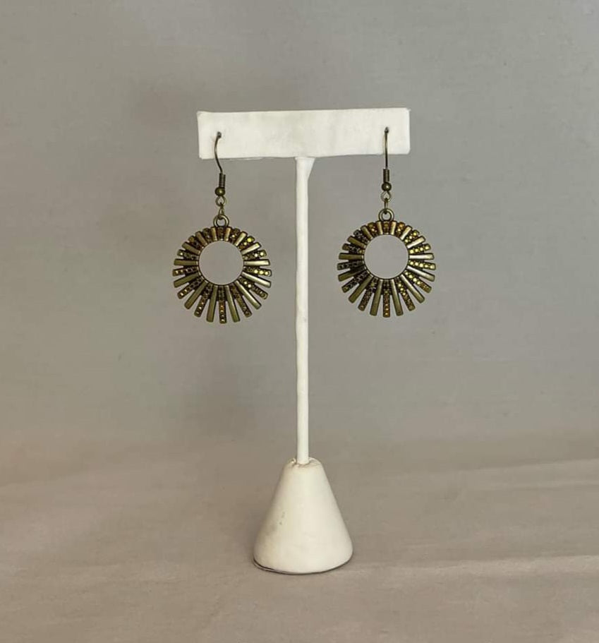 Rebel Resplendence - Brass Earrings - Paparazzi Accessories - Pressed into studded brass fittings, a collection of glittery aurum rhinestones collect inside of a hoop of brass bars, creating a sparkling frame. Earring attaches to a standard fishhook fitting. Sold as one pair of earrings.