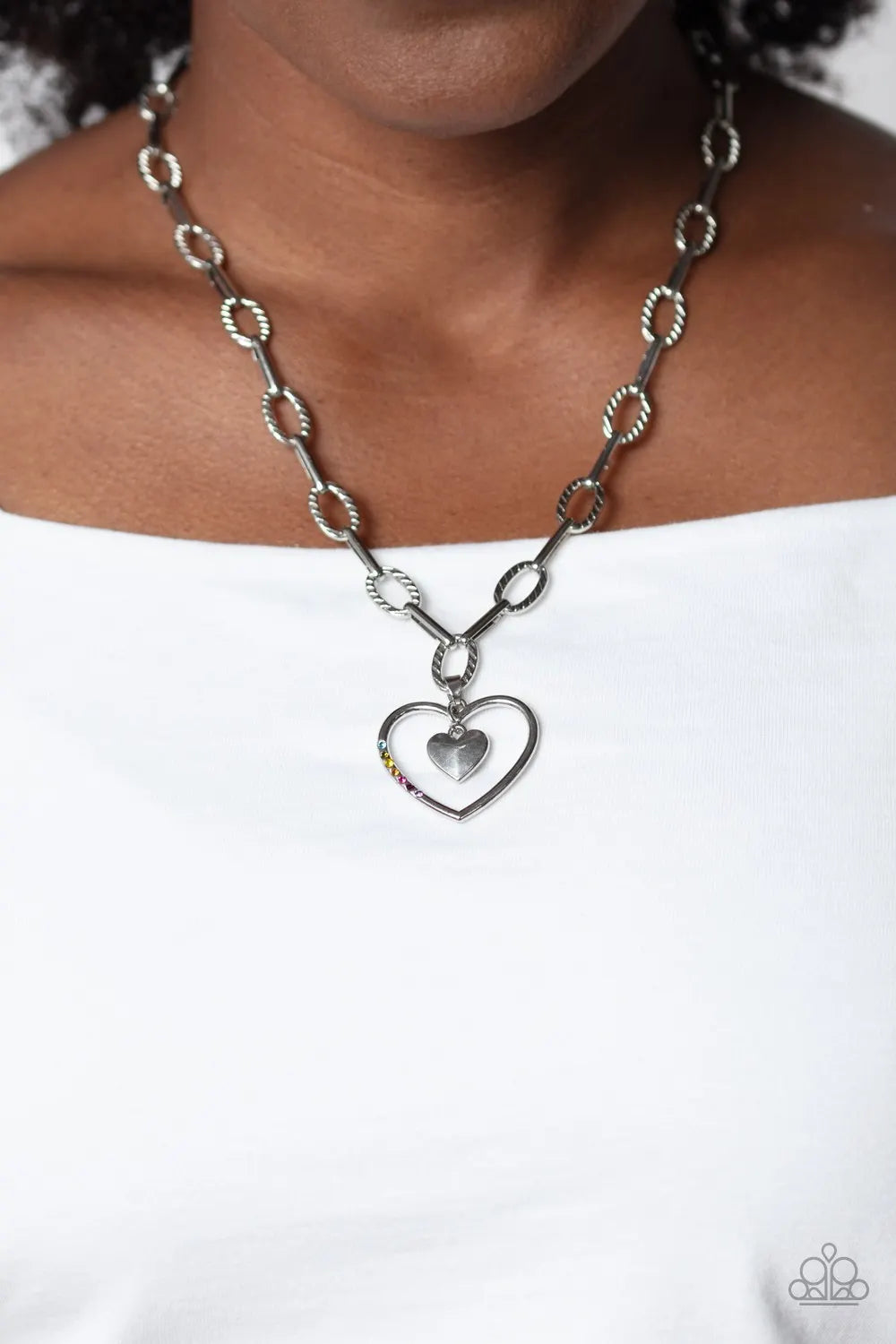 Refulgent Heart - Multi Color and Silver Necklace - Paparazzi Accessories - Textured ovals and elongated silver links lead the eye down to an oversized, airy, silver heart frame. Encrusted along one of the curves of the silver heart, dainty rhinestones glimmer for a subtle pop of color. Dangling inside the oversized heart frame, a silver heart pendant swings for a romantic finish.
