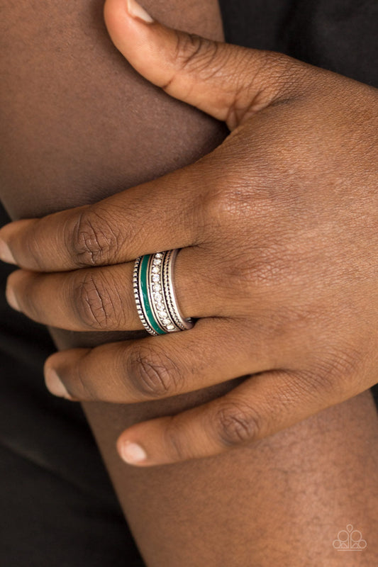 Rich Rogue - Green - Silver Ring - Paparazzi Accessories - Tinted in the rich shade of Quetzal Green, a strip of color runs along the bottom of a row of glassy white rhinestones. Infused with silver textures, the mismatched details coalesce into one thick band across the finger. Features a stretchy band for a flexible fit. Sold as one individual ring.