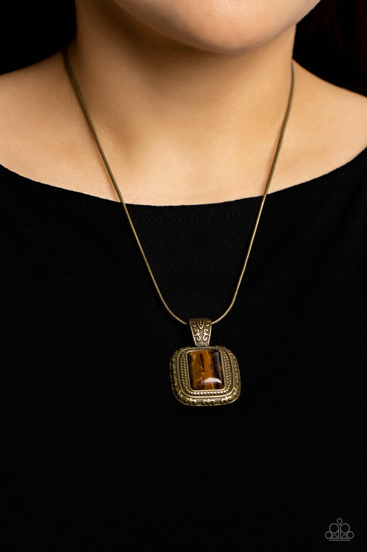 Right Hand TALISMAN - Brass Tiger Eye Necklace - Paparazzi Accessories - A rectangular tiger's eye stone is pressed into the center of a studded brass frame bordered in decorative filigree at the bottom of a rounded brass snake chain, creating a mystical talisman below the collar.