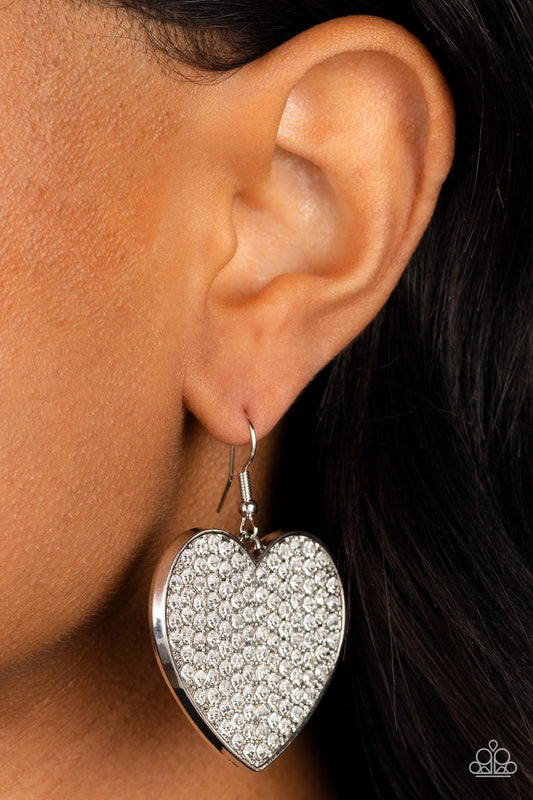 Romantic Reign - White and Silver Heart Earrings - Paparazzi Accessories - A shiny, oversized silver heart is covered in tiny white rhinestones, emitting radiant shimmer as it swings from the ear. Earring attaches to a standard fishhook fitting. Sold as one pair of earrings.