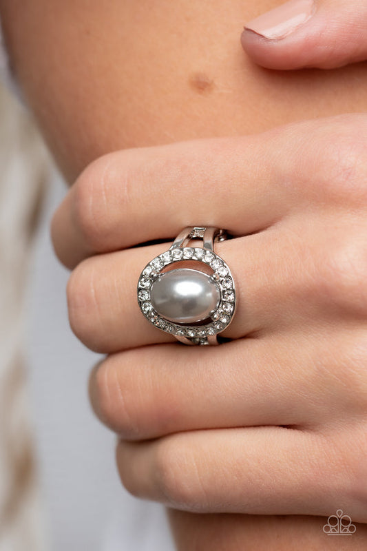 Seize the Shimmer - Silver Pearl Ring - Paparazzi Accessories - An oval silver pearl seemingly floats inside a glittery ring of white rhinestones atop layered bands of silver, resulting in a timeless centerpiece atop the finger. Features a dainty stretchy band for a flexible fit. Sold as one individual ring.