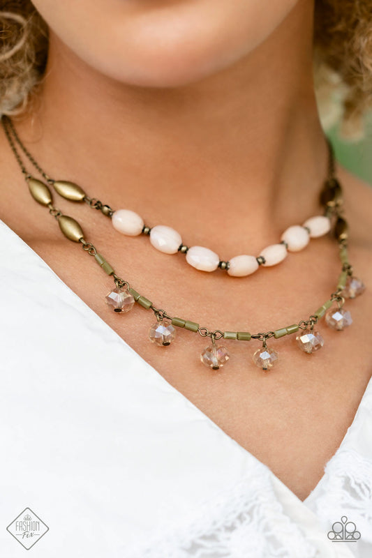 Sheen Season - Brass and Peach Necklace - Paparazzi Accessories - Two strands of dainty brass chain are adorned in a collection of peachy opaque beads, faceted glass beads, and brass accents, culminating in a layered design rich with vintage character. The glassy beads that swing along the lower chain feature a subtle reflective surface in a cozy peach glow, complementing the opaque beading that lines the chain above, with tiny brass accents sprinkled throughout the piece in a rustic finish.