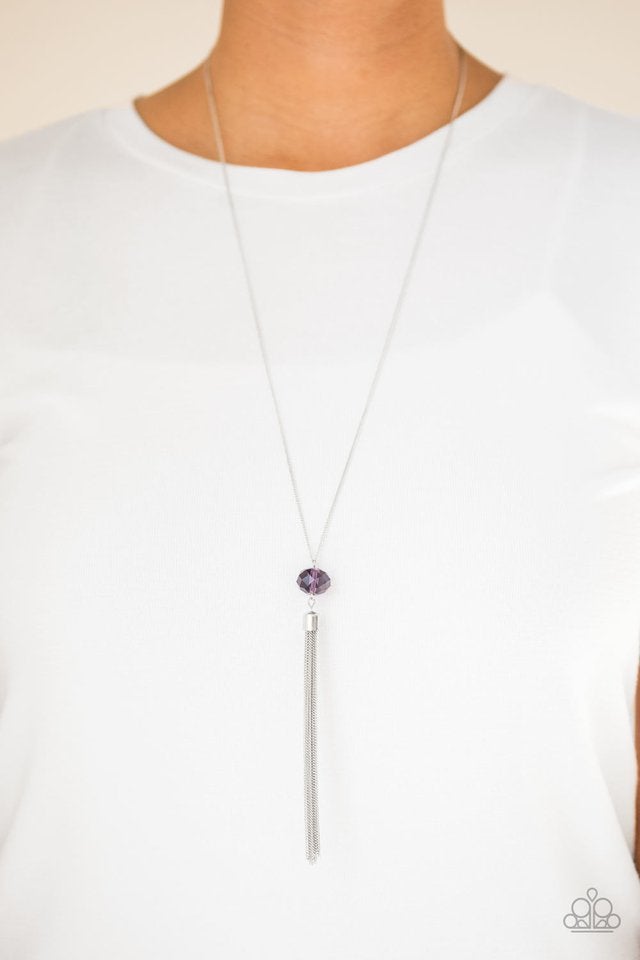 Socialite of the Season - Purple and Silver Necklace  Paparazzi Accessories - A glittery purple crystal-like bead swings from the bottom of a lengthened silver chain, giving way to a shimmering silver tassel for a glamorous finish. Features an adjustable clasp closure. Sold as one individual necklace.