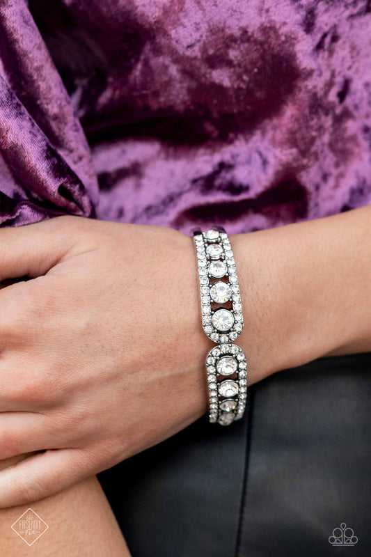 Spellbinding Splendor - White and Silver Bracelet - Paparazzi Accessories - Dazzling white rhinestones fall in line between two thick bands of silver, as they wrap around the wrist in a glitzy display. The rhinestones gradually increase in size as they lead towards the center, matching the flared ends of their silver encasement. Features a hinged closure. Sold as one individual bracelet.
