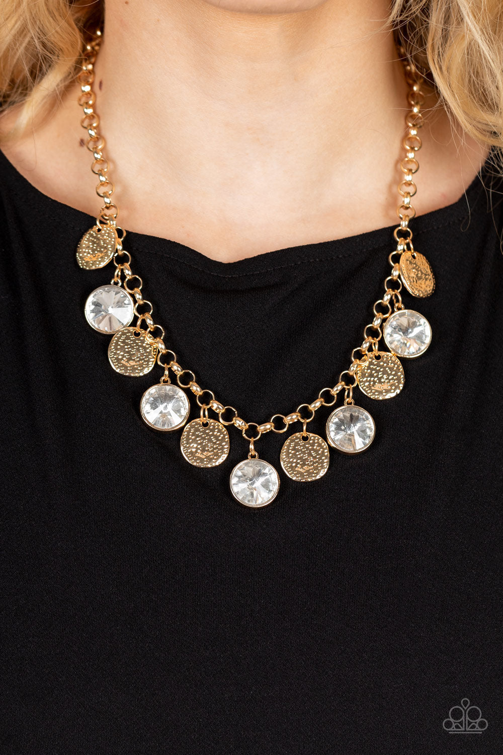 Spot On Sparkle - Gold Gem Necklace - Paparazzi Accessories - Hammered gold discs and oversized white gems swing from the bottom of a bold gold chain, creating noise-making sparkle below the collar. Features an adjustable clasp closure.