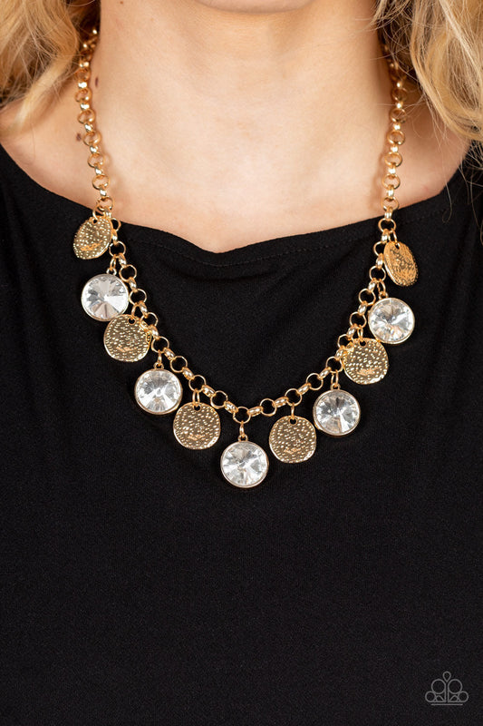 Spot On Sparkle - Gold Gem Necklace - Paparazzi Accessories - Hammered gold discs and oversized white gems swing from the bottom of a bold gold chain, creating noise-making sparkle below the collar. Features an adjustable clasp closure.