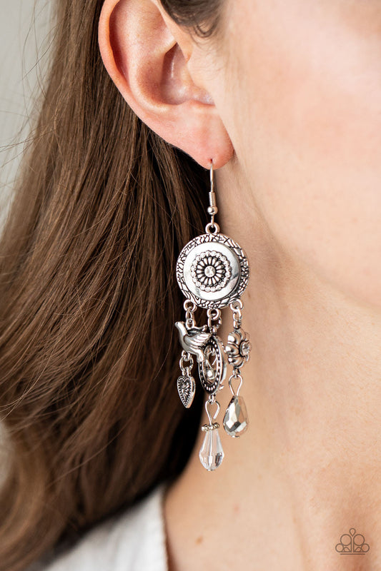 Springtime Essence - Silver Fashion Earrings - Paparazzi Accessories - Infused with glittery white rhinestones and crystal-like accents, a whimsical display of silver heart, flower, and bird charms dance from the bottom of a decorative floral silver frame, creating a noisy fringe. Earring attaches to a standard fishhook fitting. Sold as one pair of earrings.