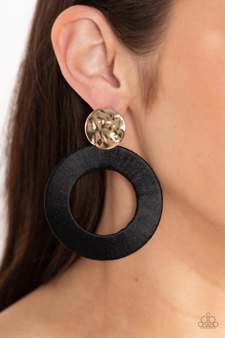 Strategically Sassy Black and Gold Earrings - Paparazzi Accessories - A hammered gold disc gives way to an oversized metal hoop wrapped in black thread, resulting in a modern lure. Earring attaches to a standard post fitting. Sold as one pair of post fashion earrings.