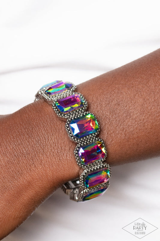 Studded Smolder - Multi Color - Oil Spill Bracelet - Paparazzi Accessories - Oversized emerald style oil spill gems are encased in antiqued studded frames that are threaded along stretchy bands around the wrist, creating a smoldering centerpiece bracelet.